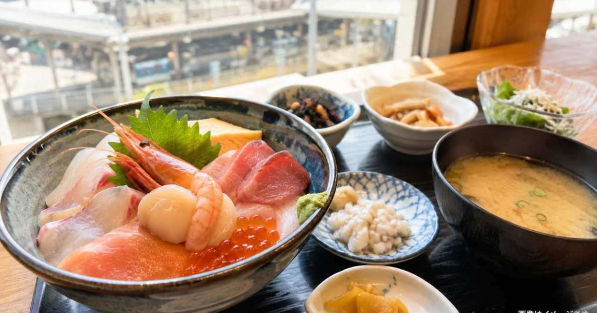 日本海を背景に新鮮な地魚やウニを盛った日御碕の海鮮丼を手前に置いた構図