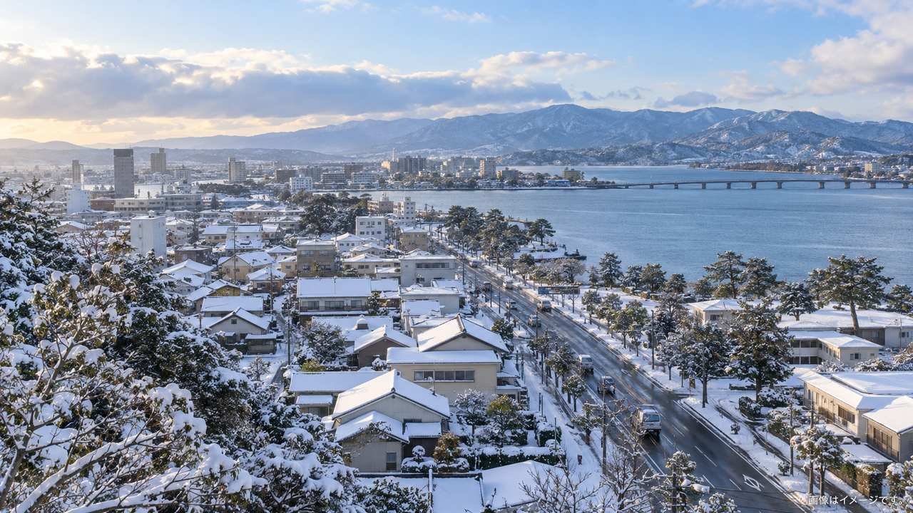 雪が積もる松江市街の道路と屋根を冬空の下で見渡した風景